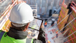 Bauleiter mit Tablet vor Ort für Inbetriebnahmemanagement gemäß VDI 6039 und AHO